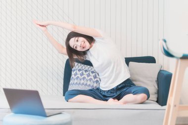 Genç Asyalı kadın oturma odasında yoga dersi alıyor.
