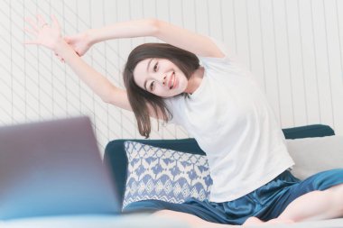 Genç Asyalı kadın oturma odasında yoga dersi alıyor.