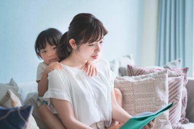 Anne ve kızı kanepede oturup resim kitabı okuyorlar.