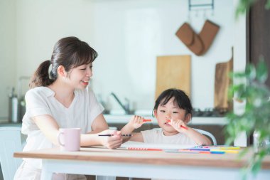 Anne ve kızı evdeki yemek masasında resim çiziyorlar.