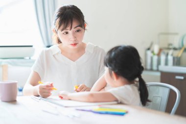 Anne ve kızı evdeki yemek masasında resim çiziyorlar.