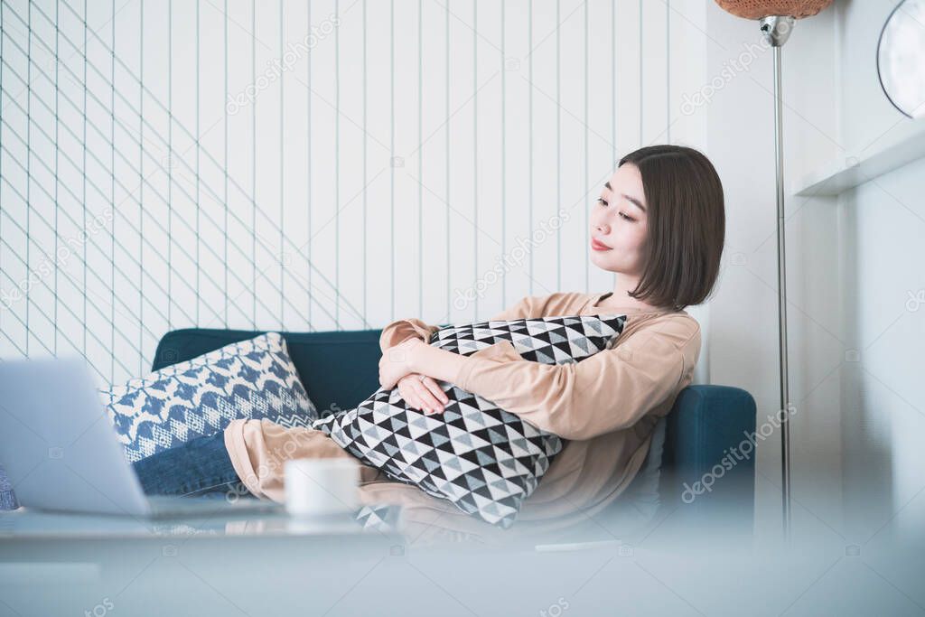 Asian young woman relaxing sitting on sofa in living room