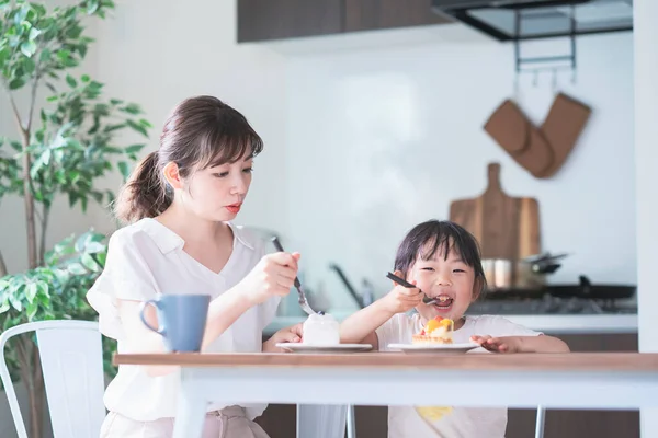 亚洲妈妈和女儿在家里的饭桌上吃蛋糕 — 图库照片