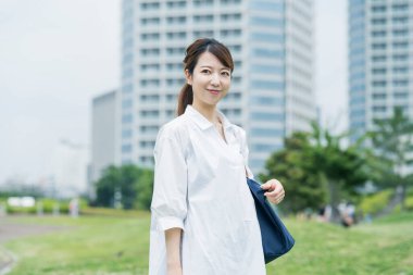 Asyalı bir kadın beyaz gömlek giyiyor ve rahatlatıcı bir atmosferde yürüyüş yapıyor.