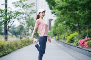 Asyalı genç bir kadın spor giyer ve bir yerleşim bölgesinde dışarıda egzersiz yapar.