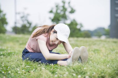 Spor giyinen ve parkta egzersiz yapan Asyalı genç bir kadın.