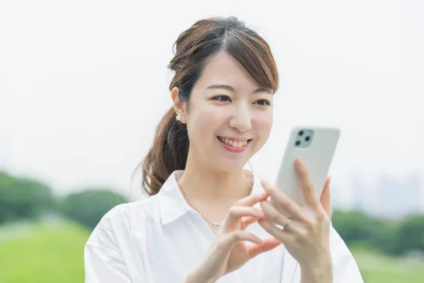 Akıllı Telefon Ekranına Bakarken Çalışan Asyalı Genç Bir Kadın — Stok fotoğraf