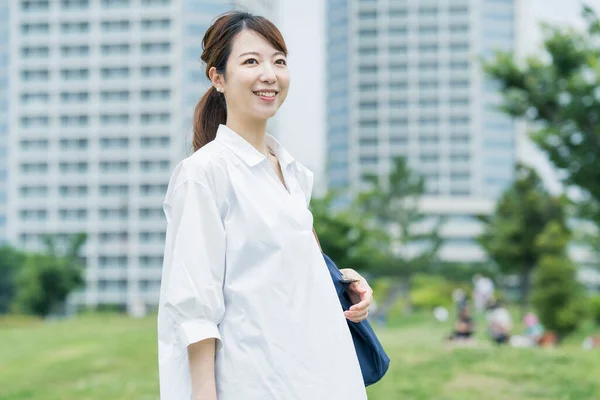 白いシャツを着てリラックスした雰囲気の中で散歩するアジアの女性 — ストック写真
