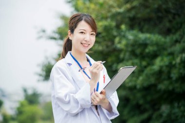 Tıbbi çizelge ve kalemle beyaz önlüklü Asyalı kadın doktor.