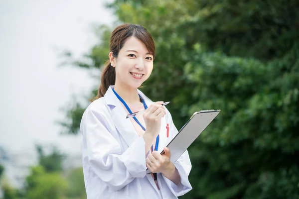 Tıbbi Çizelge Kalemle Beyaz Önlüklü Asyalı Kadın Doktor — Stok fotoğraf