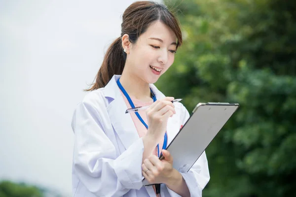 Tıbbi Çizelge Kalemle Beyaz Önlüklü Asyalı Kadın Doktor — Stok fotoğraf