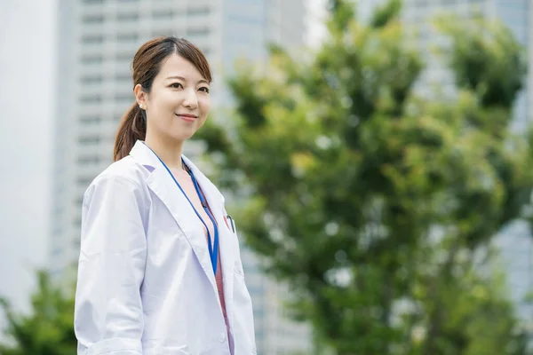 Asiatisk Kvindelig Sundhedspersonale Hvid Frakke Poserende Udendørs - Stock-foto