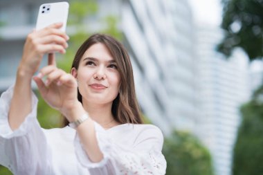 Açık havada akıllı bir telefonun ekranına dokunan ve yöneten bir kadın.