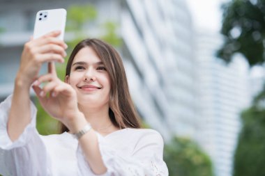 Açık havada akıllı bir telefonun ekranına dokunan ve yöneten bir kadın.