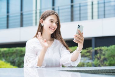 Kadın akıllı telefonu gülümseyerek video görüşmesi yapmak için kullanıyor.