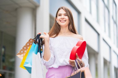 Şehirde bir sürü alışveriş çantasıyla dolaşan genç bir kadın.