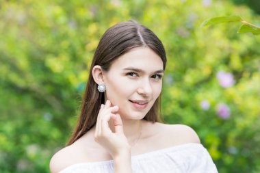 Beyaz omuzlu ve bitkilerle çevrili genç bir kadın.