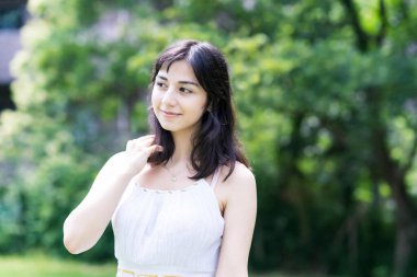 Yeşil bir alanda rahat bir yüz ifadesi gösteren genç bir kadın.