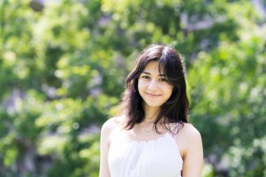 Yeşil bir alanda rahat bir yüz ifadesi gösteren genç bir kadın.