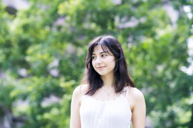 Yeşil bir alanda rahat bir yüz ifadesi gösteren genç bir kadın.