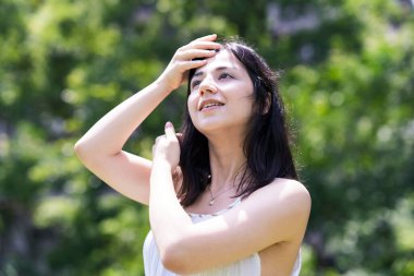 Yeşil bir alanda rahat bir yüz ifadesi gösteren genç bir kadın.