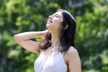 Yeşil bir alanda rahat bir yüz ifadesi gösteren genç bir kadın.