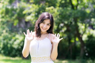 Genç kadın yeşil bir gülümsemeyle kameraya poz veriyor.