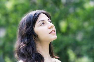 Yeşil bir alanda rahat bir yüz ifadesi gösteren genç bir kadın.