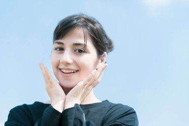 Gülümseyen ve mavi gökyüzüne dokunan bir kadın.