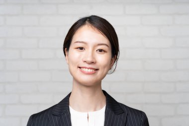 Takım elbise giymiş gülümseyen Asyalı genç bir iş kadınının portresi.