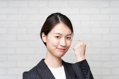 Takım elbiseli, gülümseyen ve tezahürat yapan Asyalı genç iş kadını.