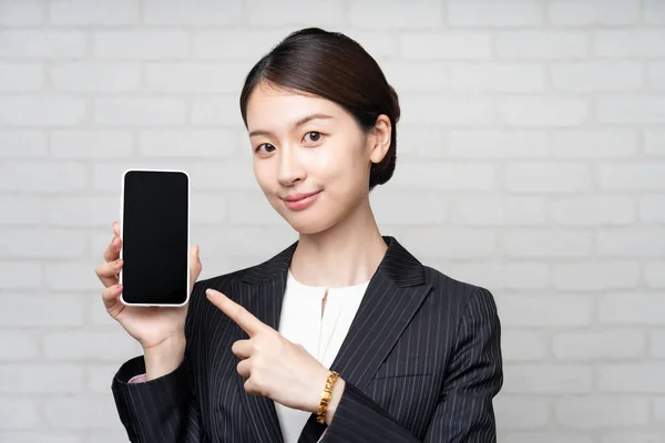 スマートフォンの画面を操作スーツのアジアの若いビジネス女性 — ストック写真
