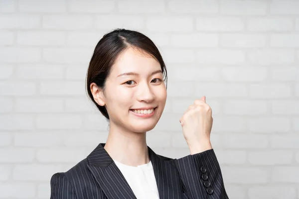 Asian young business woman in a suit posing with a smile and cheering