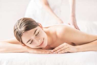 Genç bir kadın, parlak bir atmosferde güzellik salonunda masaj yaptırıyor.