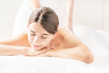 Genç bir kadın, parlak bir atmosferde güzellik salonunda masaj yaptırıyor.