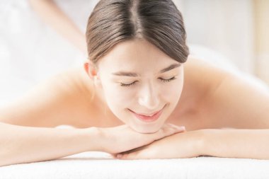 Genç bir kadın, parlak bir atmosferde güzellik salonunda masaj yaptırıyor.