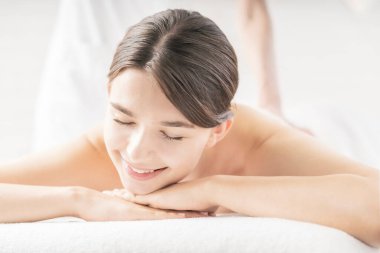 Genç bir kadın, parlak bir atmosferde güzellik salonunda masaj yaptırıyor.