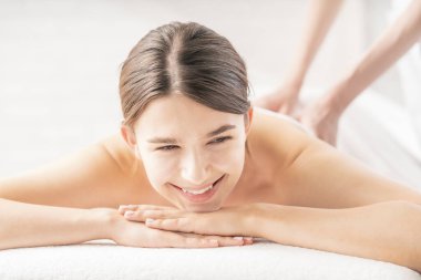 Genç bir kadın, parlak bir atmosferde güzellik salonunda masaj yaptırıyor.