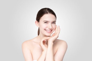 Asyalı genç bir kadın, sakin bir ifadeyle yüzüne dokunuyor.