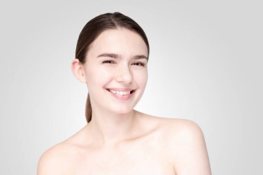 Beyaz arka planda duran, rahat bakışlı genç kadın.