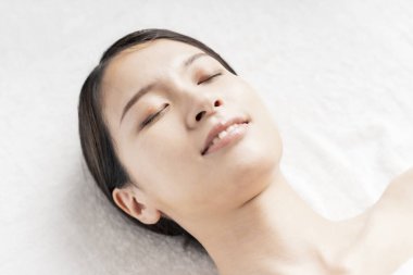 Güzellik salonunda uzanmış genç bir kadının rahat yüzü.