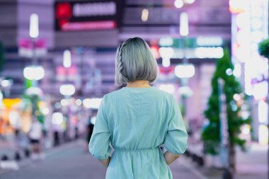 Gece Tokyo 'nun parıldayan şehrinde poz veren genç kadın