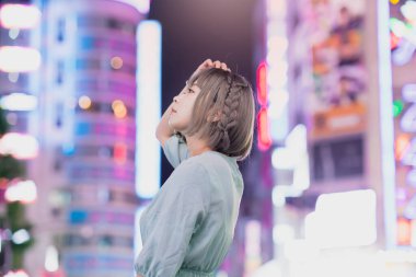 Gece Tokyo 'nun parıldayan şehrinde poz veren genç kadın