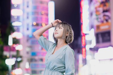 Gece Tokyo 'nun parıldayan şehrinde poz veren genç kadın