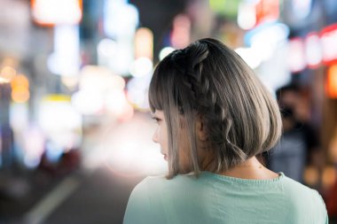 Gece Tokyo 'nun parıldayan şehrinde poz veren genç kadın