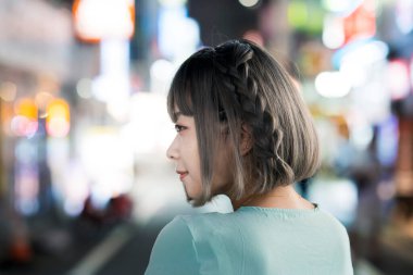 Gece Tokyo 'nun parıldayan şehrinde poz veren genç kadın