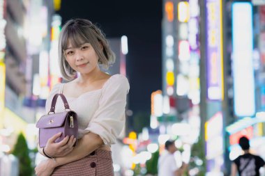 Gece Tokyo 'nun parıldayan şehrinde poz veren genç kadın