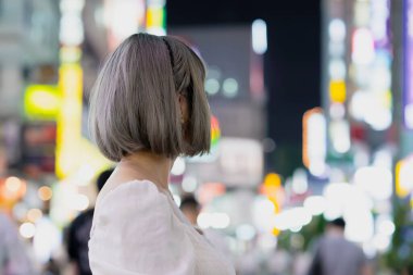 Gece Tokyo 'nun parıldayan şehrinde poz veren genç kadın