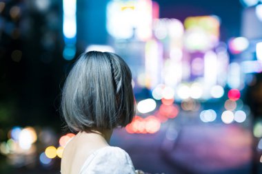 Gece Tokyo 'nun parıldayan şehrinde poz veren genç kadın