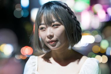 Gece Tokyo 'nun parıldayan şehrinde poz veren genç kadın